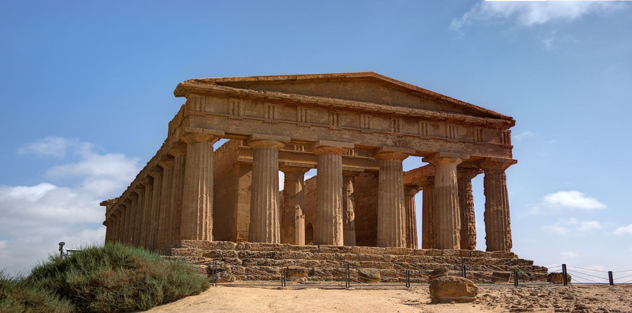 «Ο Ναός της Ομόνοιας στην Κοιλάδα των Ναών, Αγκριτζέντο, με τη χαρακτηριστική δωρική πρόσοψη και τους λαξευμένους κίονες κάτω από γαλανό ουρανό.»