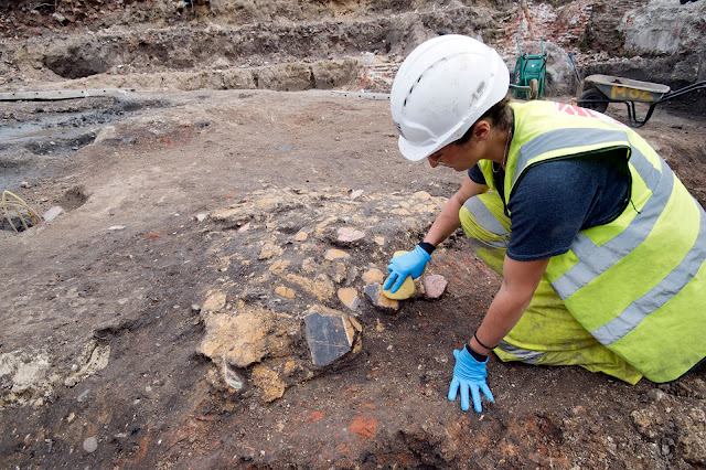 Αρχαιολόγος ανασύρει θραύσματα αρχαίας ρωμαϊκής τοιχογραφίας κατά τη διάρκεια ανασκαφής στο Λονδίνο.