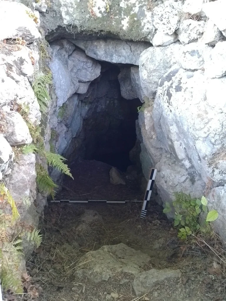 Άποψη της υπόγειας μυκηναϊκής κρήνης στη Σχολή Ομήρου στην Ιθάκη, με είσοδο λαξευμένη στον βράχο και ογκόλιθους να οριοθετούν το άνοιγμα.