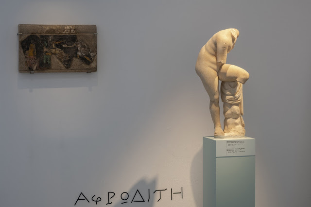 Άγαλμα της Αφροδίτης σε έκθεση του Αρχαιολογικού Μουσείου Θήρας, τοποθετημένο σε βάθρο, με επιγραφή στο δάπεδο.