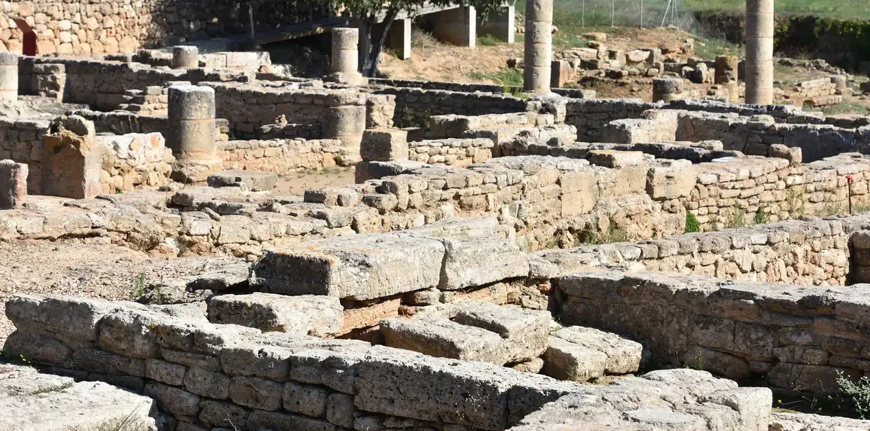 Ερείπια ρωμαϊκής κατασκευής στην αρχαία Pollentia της Μαγιόρκα, με εμφανείς πέτρινους τοίχους και κίονες, κάτω από τον ήλιο της Μεσογείου.