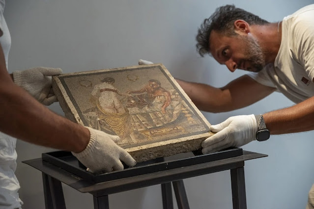 Δύο συντηρητές με λευκά γάντια τοποθετούν προσεκτικά ρωμαϊκό ψηφιδωτό που απεικονίζει ζευγάρι σε ερωτική σκηνή, στο μουσείο της Πομπηίας.