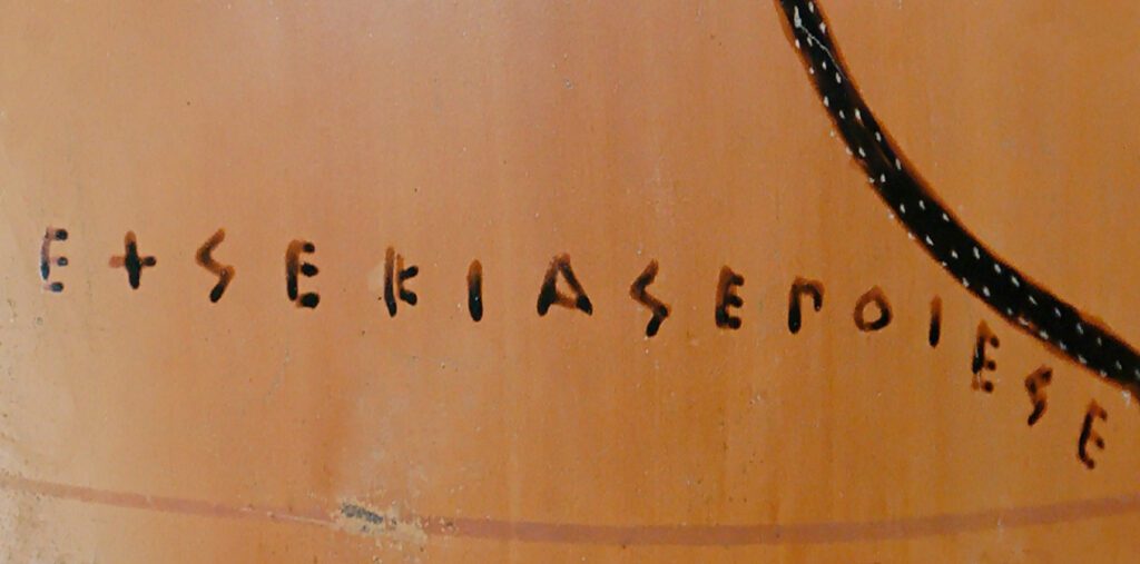 Κοντινή φωτογραφία της υπογραφής του Εξηκία σε αρχαίο ελληνικό αγγείο, γραμμένη με μαύρα αρχαϊκά γράμματα: «ΕΧΣΕΚΙΑΣ ΕΠΟΙΕΣΕΝ».