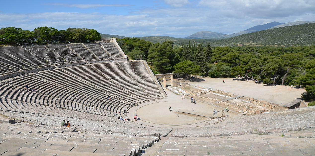 Το Αρχαίο Θέατρο της Επιδαύρου, ένα καλά διατηρημένο αρχαίο ελληνικό θέατρο με πέτρινες κερκίδες, μέσα σε καταπράσινο φυσικό τοπίο.