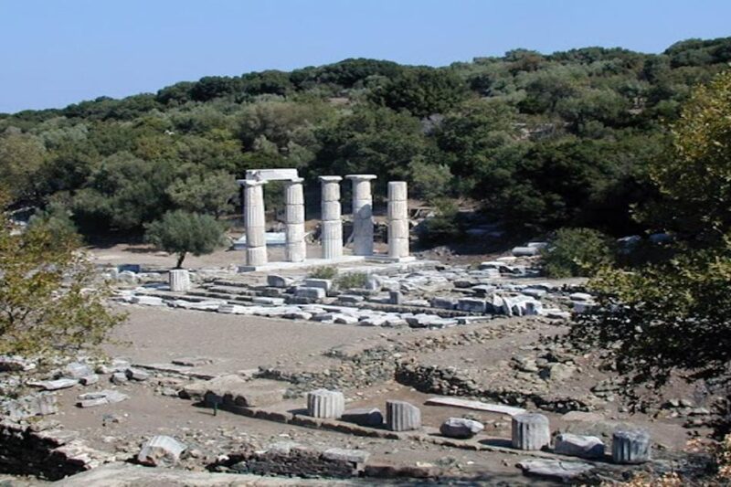 Ερείπια και αναστηλωμένες κολώνες του Ιερού των Μεγάλων Θεών στη Σαμοθράκη, μέσα σε φυσικό περιβάλλον με πυκνή βλάστηση.