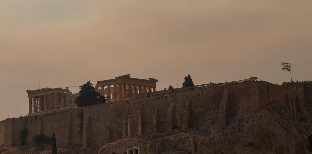 Καπνός από φωτιά καλύπτει τον ουρανό πάνω από την Ακρόπολη της Αθήνας.