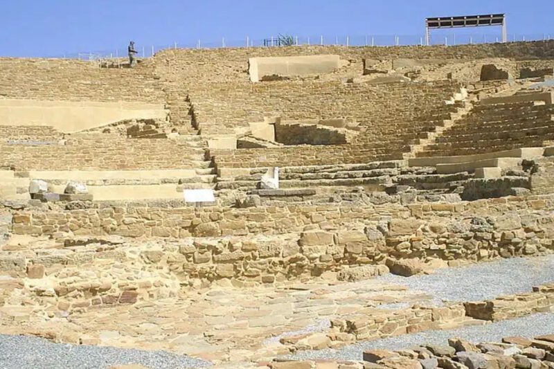 Ηφαιστία Λήμνου: Η Αρχαία Πόλη του Θεού Ηφαίστου - Άποψη των πέτρινων ερειπίων και των αναστηλωμένων κερκίδων του αρχαίου θεάτρου της Ηφαιστίας στη Λήμνο, κάτω από έναν καθαρό γαλάζιο ουρανό.