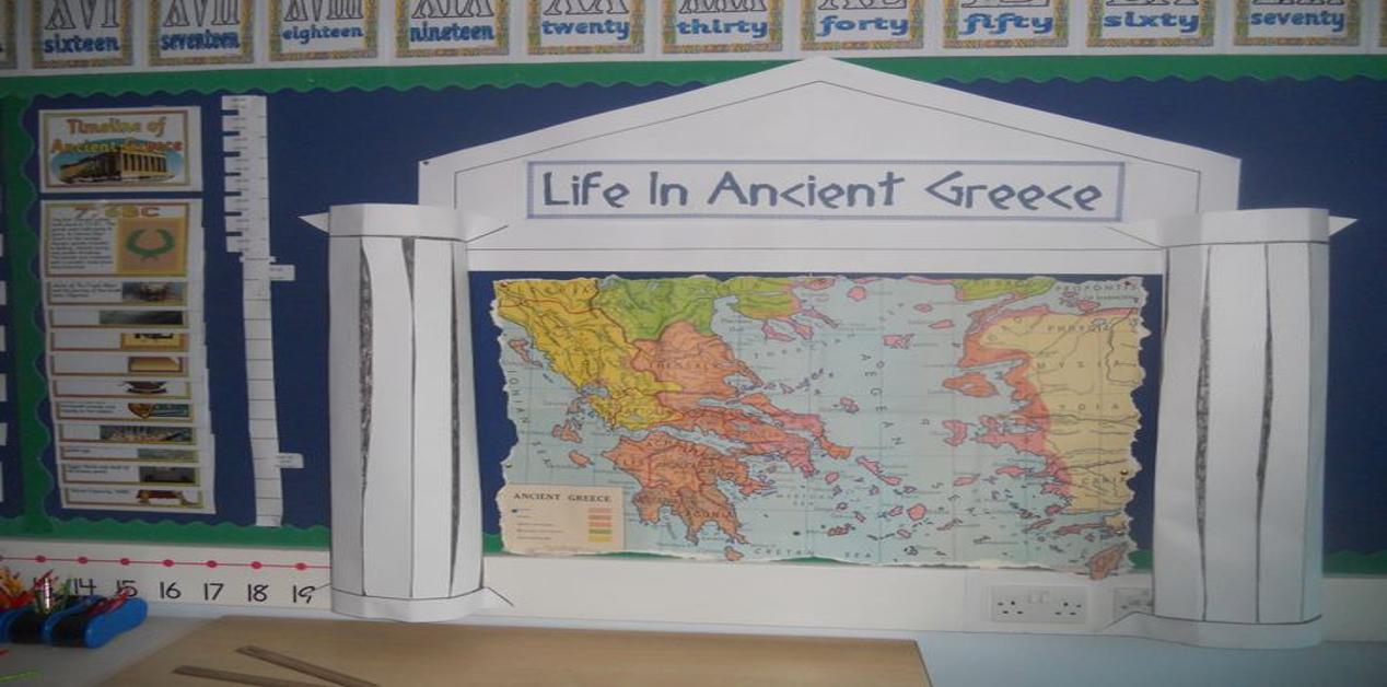 Σχολικός πίνακας με τίτλο ‘Life in Ancient Greece’, χάρτη της αρχαίας Ελλάδας και διακόσμηση με κλασικές κολόνες, συμβολισμός της ελληνικής παιδείας.