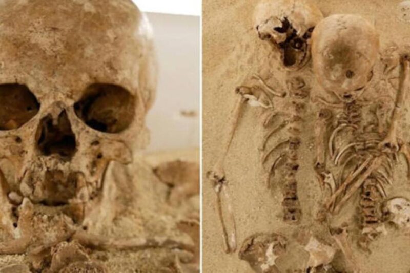 Ανθρώπινος σκελετός σε αρχαία ταφή με δεύτερο κρανίο τοποθετημένο κοντά στο σώμα, αποκαλύπτοντας σπάνιο ταφικό έθιμο προϊστορικής περιόδου.
