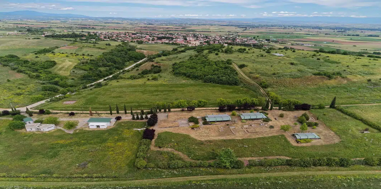 Πανοραμική αεροφωτογραφία του αρχαιολογικού χώρου της Ευρωπού με στέγαστρα προστασίας και το σύγχρονο χωριό στο βάθος.