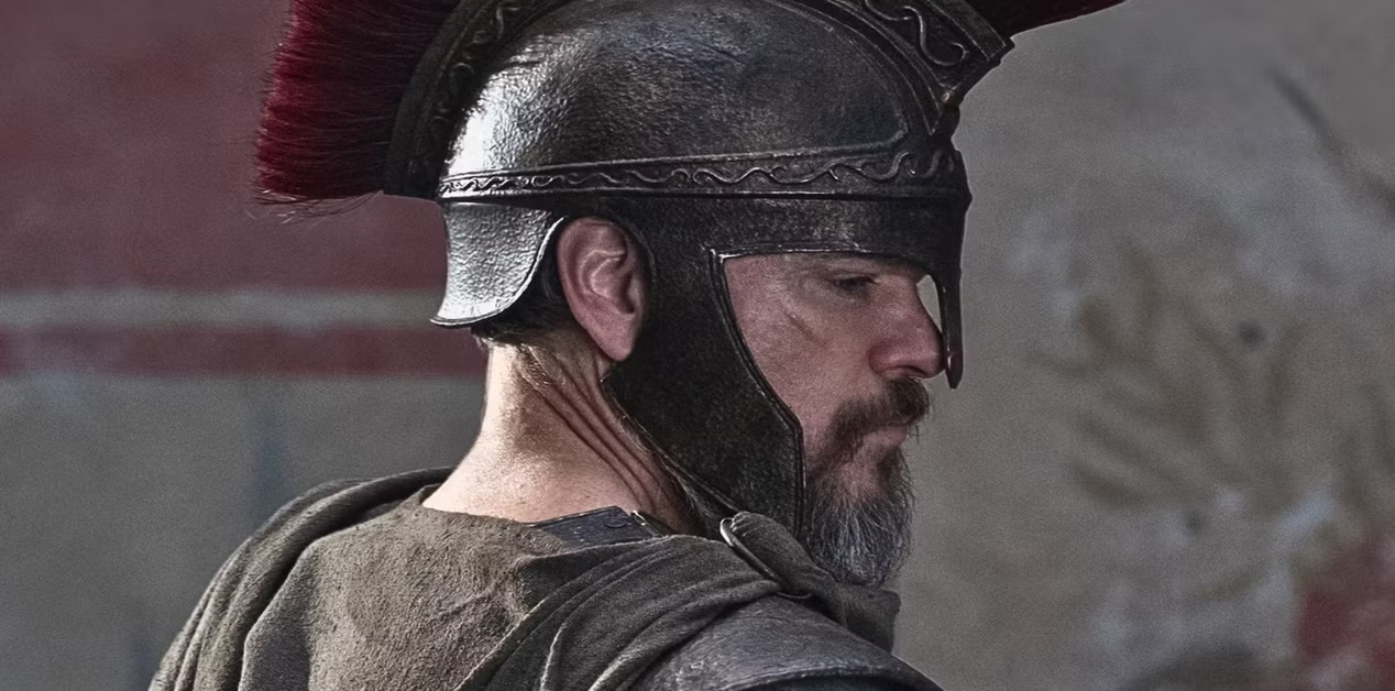 Κοντινό προφίλ ενός άνδρα με αρχαιοελληνικό στρατιωτικό κράνος με κόκκινο λοφίο, που απεικονίζει τον Οδυσσέα σε μια κινηματογραφική ατμόσφαιρα.