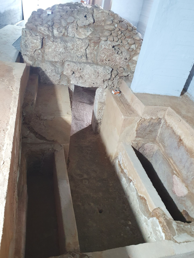 Άποψη του εξωτερικού μέρους ενός αρχαίου Μακεδονικού τάφου από ψηλά. Διακρίνεται η θολωτή κατασκευή (καμάρα) από ακατέργαστους λίθους, το στενό πέρασμα της εισόδου και δύο κτιστοί λάκκοι ή θήκες εκατέρωθεν του διαδρόμου πρόσβασης.