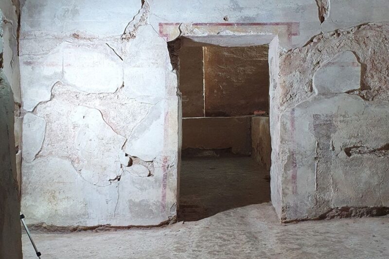 Εσωτερική άποψη αρχαίου Μακεδονικού τάφου στη Δράμα. Διακρίνεται ο προθάλαμος με το πέρασμα προς τον κυρίως θάλαμο, οι φθαρμένοι σοβάδες στους τοίχους και τα ίχνη κόκκινης γραμμικής διακόσμησης γύρω από το άνοιγμα της θύρας.