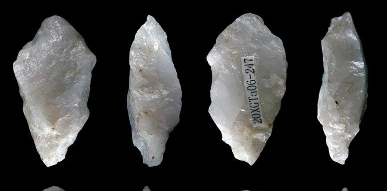Τέσσερις όψεις ενός αρχαίου λίθινου εργαλείου από ημιδιαφανή λευκό χαλαζία, με αιχμηρές απολήξεις και εμφανή σημάδια επεξεργασίας, σε μαύρο φόντο.