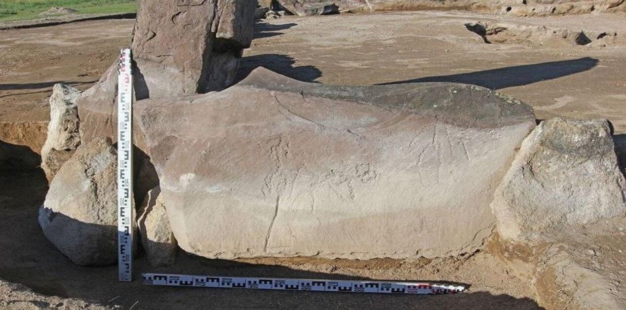 Πέτρινη πλάκα με αρχαία πετρογλυφικά και κλίμακες μέτρησης σε αρχαιολογική ανασκαφή σε ταφικό τύμβο στη Χακασία της Σιβηρίας.