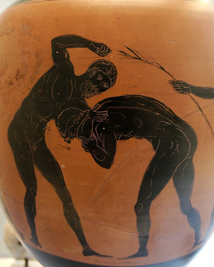 Λεπτομέρεια από μελανόμορφο Παναθηναϊκό αμφορέα που απεικονίζει δύο γυμνούς αθλητές να αγωνίζονται στο παγκράτιο. Ο ένας κρατά τον άλλον σε λαβή κεφαλιού, ενώ στα δεξιά διακρίνεται το χέρι ενός κριτή με ράβδο.