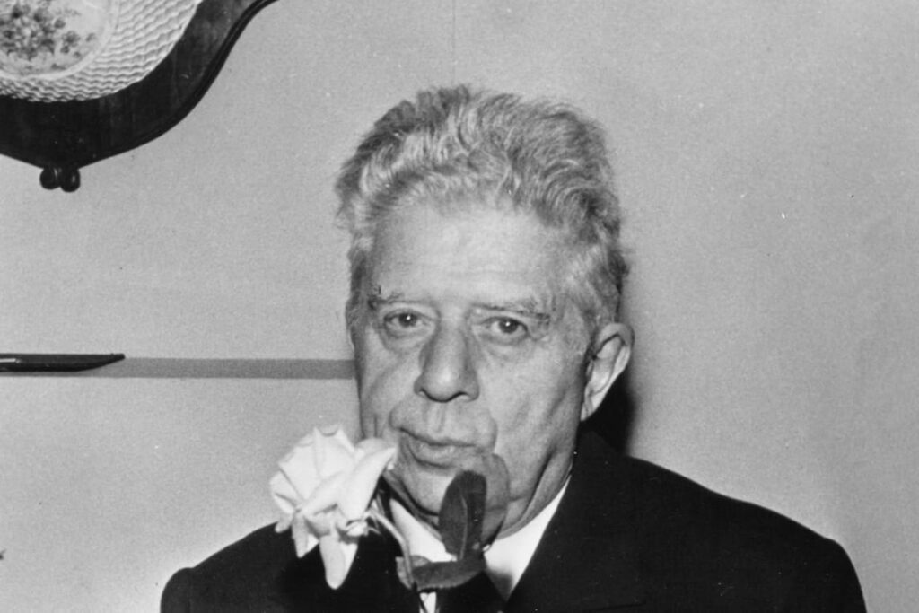 Ασπρόμαυρο πορτρέτο του νομπελίστα Ιταλού ποιητή Εουτζένιο Μοντάλε να κρατά ένα λευκό λουλούδι.