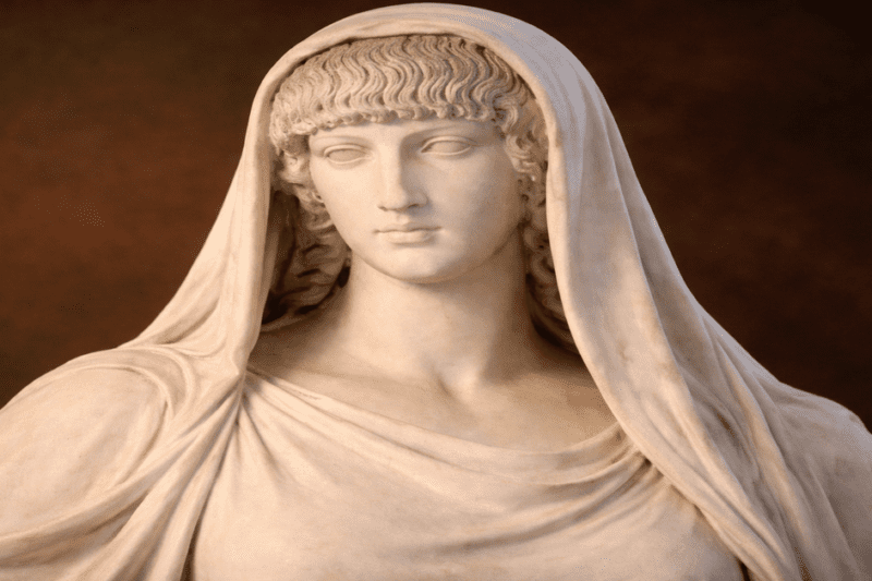 Κοντινό πλάνο μαρμάρινης προτομής και κεφαλής αγάλματος της θεάς Εστίας, με πέπλο.