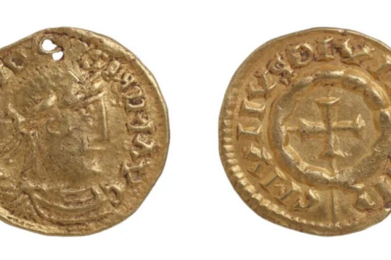 Φωτογραφία των δύο όψεων ενός χρυσού νομίσματος-μενταγιόν από την εποχή των Βίκινγκ, με δύο ορατές τρύπες. Η μία όψη δείχνει το προφίλ ενός προσώπου και η άλλη έναν σταυρό.