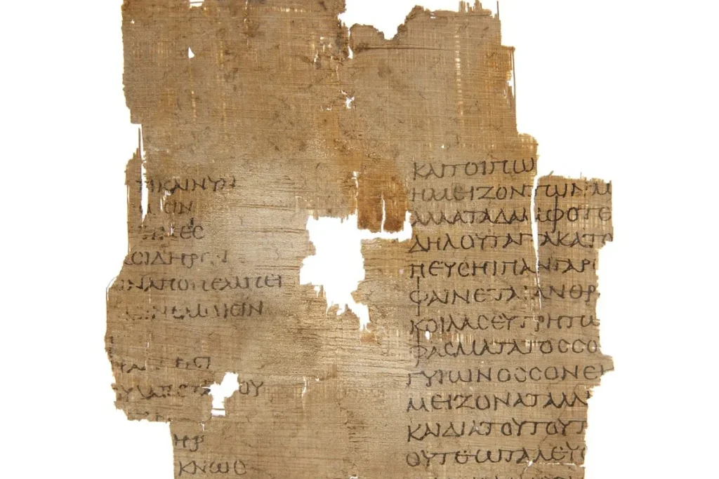 Φθαρμένο κομμάτι αρχαίου παπύρου με εμφανή ελληνικά γράμματα χειρόγραφης γραφής.