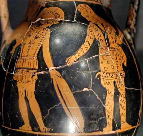 Λεπτομέρεια από σπασμένο και αναστηλωμένο ερυθρόμορφο αγγείο που δείχνει δύο άνδρες με πανοπλία, χιτώνες και κράνη να στέκονται αντικριστά.
