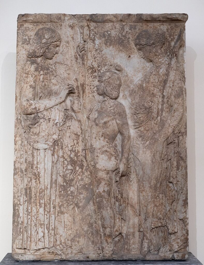 Φθαρμένο μαρμάρινο ανάγλυφο (το Μεγάλο Ανάγλυφο της Ελευσίνας) που δείχνει τη Δήμητρα, τον Τριπτόλεμο και την Περσεφόνη.