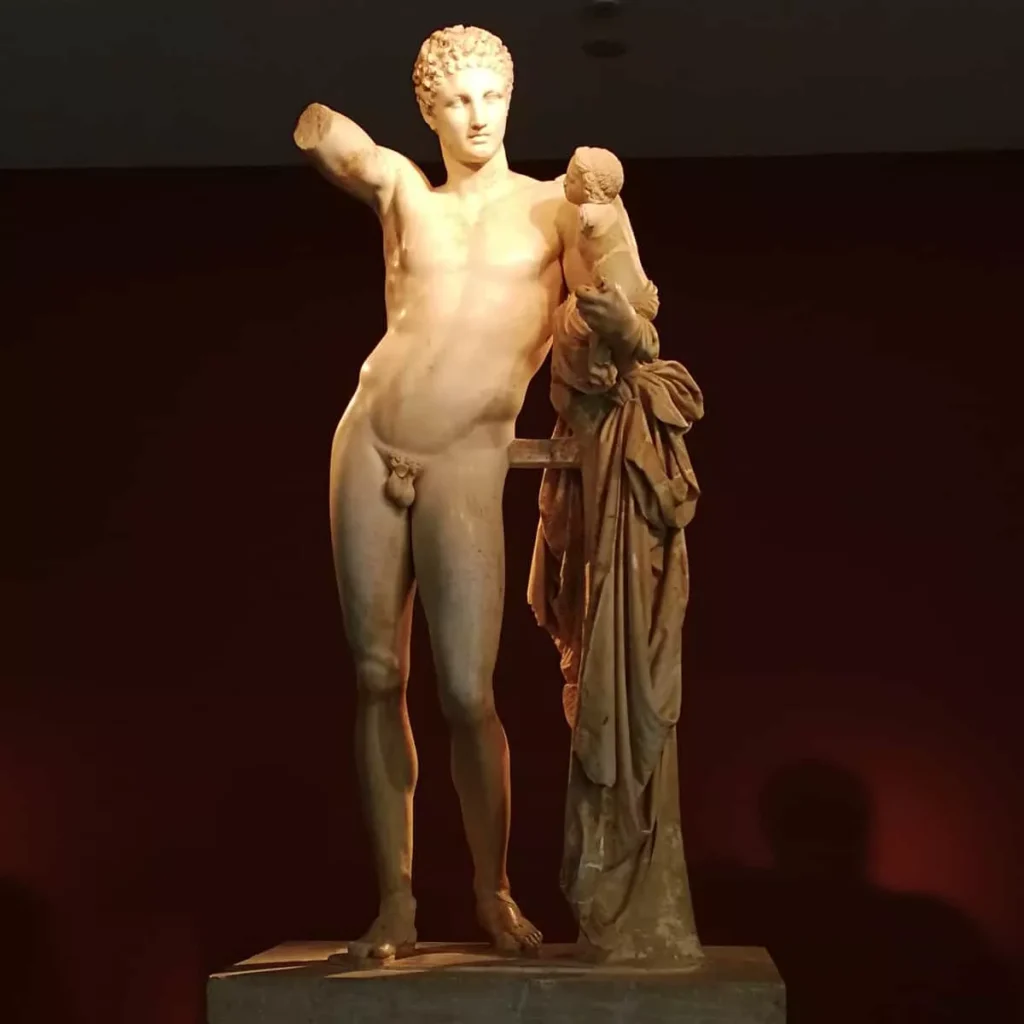 Φωτογραφία του ολόσωμου μαρμάρινου αγάλματος του Ερμή του Πραξιτέλη σε μουσείο.