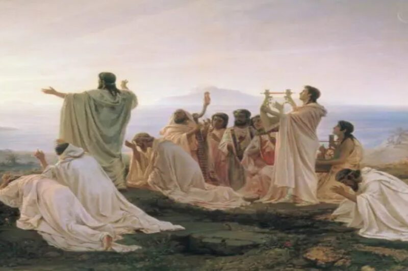 Ένας κλασικός πίνακας ζωγραφικής που απεικονίζει μια ομάδα ανθρώπων με λευκούς αρχαίους χιτώνες συγκεντρωμένους σε έναν βράχο πάνω από τη θάλασσα. Κάποιοι προσεύχονται γονατιστοί και άλλοι παίζουν λύρες, ενώ μια κεντρική φιγούρα με απλωμένα χέρια υποδέχεται το φως της ανατολής του ηλίου.