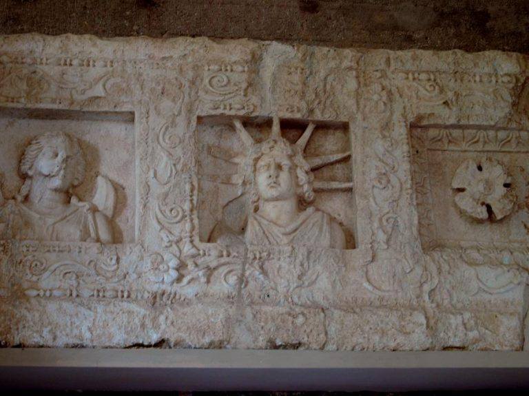 Πέτρινο ανάγλυφο με τρία πλαίσια, στο κεντρικό απεικονίζεται ο θεός Ήλιος με έντονες ηλιακές ακτίνες.