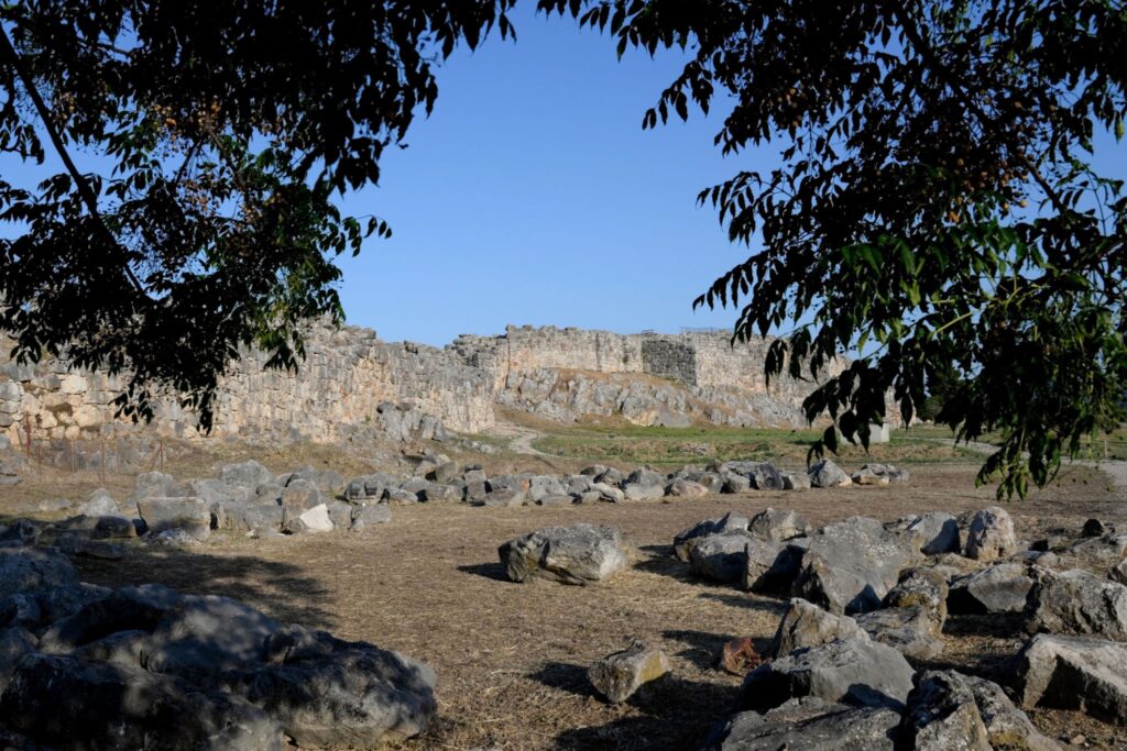 Ερείπια των μυθικών Κυκλώπειων τειχών της αρχαίας Τίρυνθας μέσα από φυλλωσιές δέντρων.
