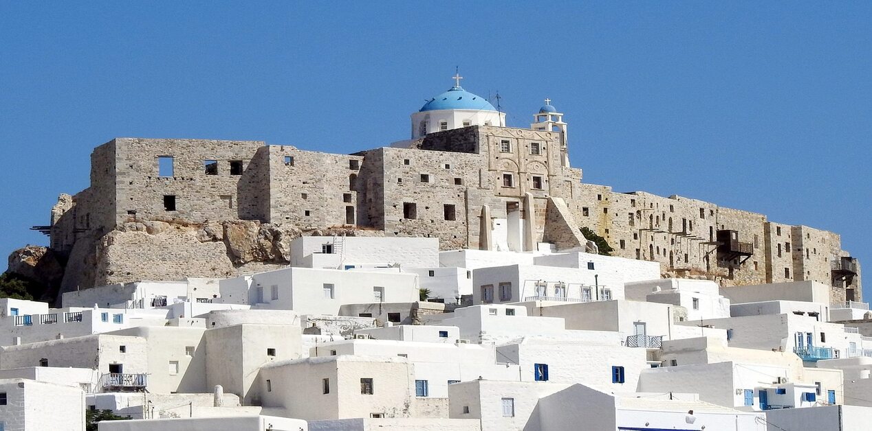 Ενετικό Κάστρο των Κουερίνι και παραδοσιακά λευκά σπίτια στη Χώρα της Αστυπάλαιας κάτω από τον γαλάζιο ουρανό.